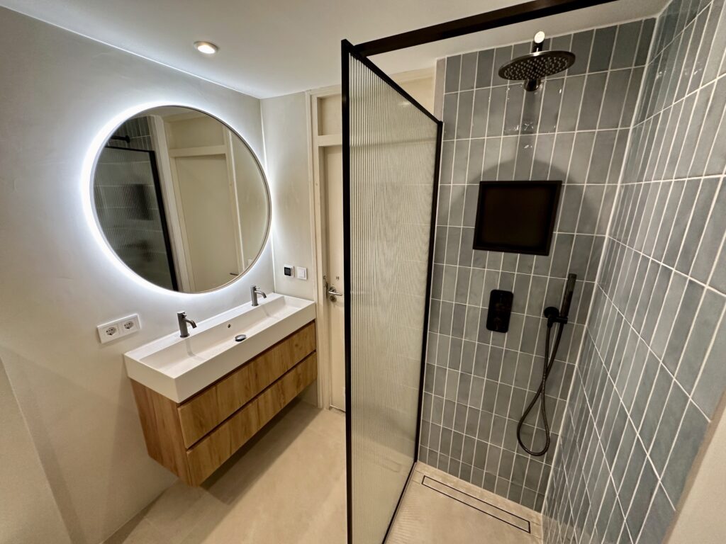Home Luxe badkamer met beton ciré, handgebakken wandtegels, inloopdouche met nis en eikenhouten badkamermeubel, gerealiseerd door Bulder Klusbedrijf.