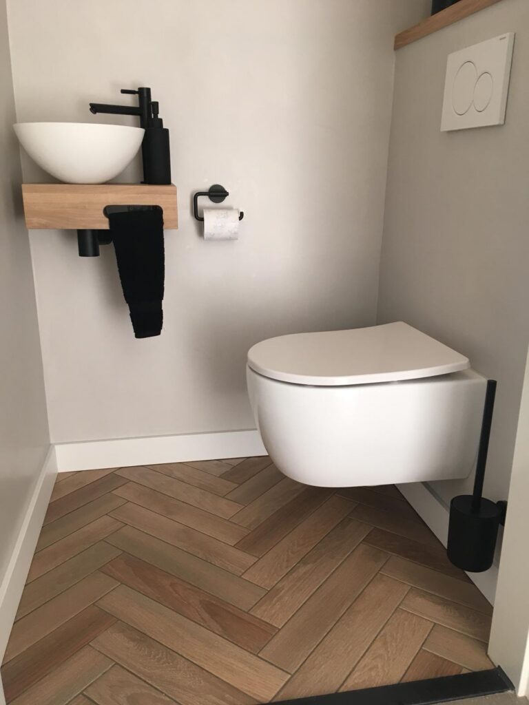 Exclusieve badkamerrenovatie met beton ciré in Amstelveen Keramische visgraatvloer met houtlook in een modern zwevend toilet met beton ciré wanden in Amstelveen