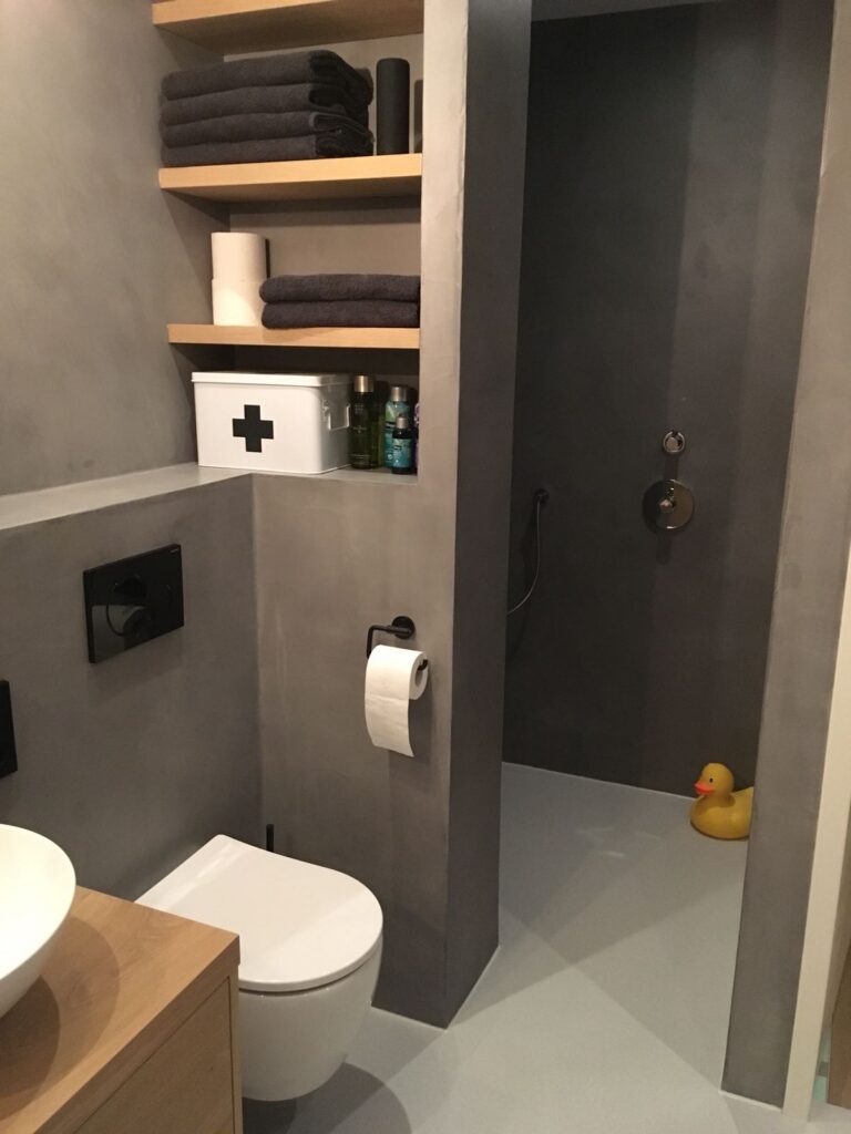 Exclusieve badkamerrenovatie met beton ciré in Amstelveen Luxe inloopdouche met beton ciré wanden, ingebouwde nissen van eikenhout en een modern tweede zwevend toilet in Amstelveen